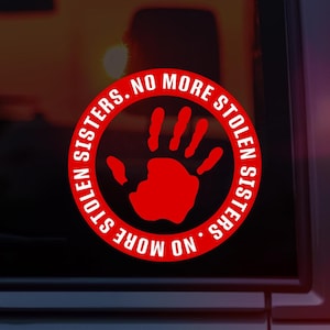 Può includere: Adesivo circolare rosso con il testo "No More Stolen Sisters" e un'impronta di mano rossa al centro. L'adesivo è sul finestrino di un'auto.