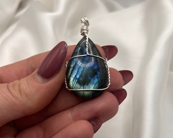 Può includere: Un ciondolo a forma di lacrima in labradorite avvolto in filo d'argento.
