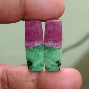 May include: Two rectangular cabochons featuring a distinct color split with a vibrant magenta-pink top section and a bright green bottom section, accented by small black mineral inclusions throughout the lower green portion of the stones.