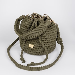 Olivgrüne Bucket Bag - eine gehäkelte Rundbodentasche mit Kordelzug, langen und kurzen Makrameebändern und metallenen Reifen