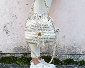 Beige/natuurlijk gestreepte bucket bag - een handgemaakte gehaakte tas met ronde bodem en trekkoord met lange en korte macramériemen en metalen hoepels