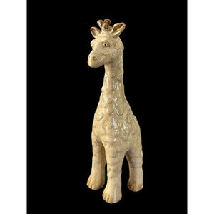 May include: A ceramic giraffe figurine with a cream-colored body and brown accents. The giraffe has a long neck, small ears, and a textured surface. The figurine is standing on four legs and has a slightly whimsical appearance.