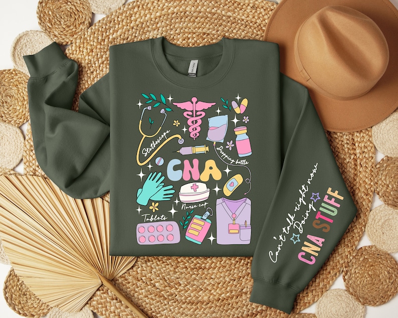 May include: A green sweatshirt with a colorful graphic design of medical tools and the text "CNA" in large letters. The right sleeve has the text "Can't talk right now Doing CNA STUFF".