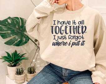 Może przedstawiać: Beżowa bluza z nadrukiem "I have it all TOGETHER I just forgot where I put it" w ciemnoniebieskim kolorze.