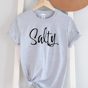 May include: Gray t-shirt with the word "Salty" written in black script.