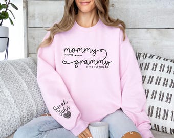 May include: Pink sweatshirt with the text "mommy est 1999" and "grammy est 2006" on the front and the text "Sarah John" on the left sleeve.