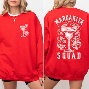 Peut inclure: Sweat-shirt rouge avec un graphique blanc d'un verre &agrave; margarita et le texte "Margarita Squad" au dos.