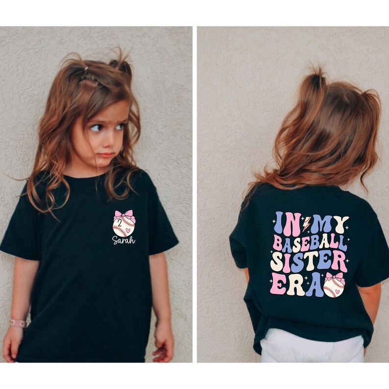 Może przedstawiać: Czarny T-shirt z r&oacute;żowym nadrukiem baseballu i imieniem "Sarah" z przodu. Z tyłu T-shirt ma napis "In My Baseball Sister Era" w kolorach tęczy z r&oacute;żowym nadrukiem baseballu.