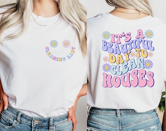 May include: White t-shirt with a smiley face made of flowers and the text "Cleaning Lady" on the front. The back of the shirt has the text "It's a beautiful day to clean houses" with flowers around the text.
