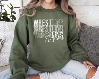 以下が含まれることがあります： 白い文字で「Wrestling Mama」と書かれた緑色のスウェットシャツ。テキストは「Wrestling」という単語を3回繰り返して縦に積み重ねられています。
