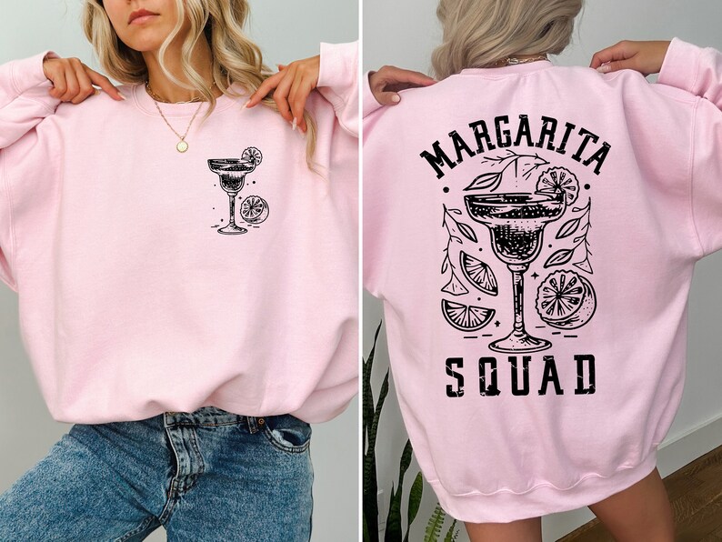 Peut inclure: Sweat-shirt rose avec un graphique noir d'un verre &agrave; margarita avec des tranches de citron vert et le texte "Margarita Squad" au dos.