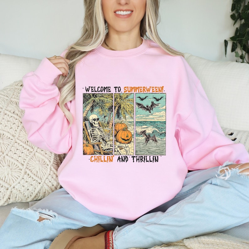 May include: Pink sweatshirt with a graphic that reads "WELCOME TO. SUMMERWEEN!" and "CHILLIN AND THRILLIN". The graphic features a skeleton relaxing on a beach, pumpkins, bats, and a wave with a bat.