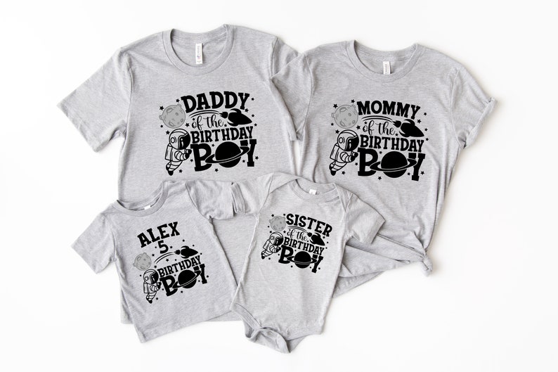 May include: Set of four grey t-shirts with black astronaut and planet designs. The shirts say "Daddy of the Birthday Boy", "Mommy of the Birthday Boy", "Sister of the Birthday Boy", and "Alex 5 Birthday Boy".