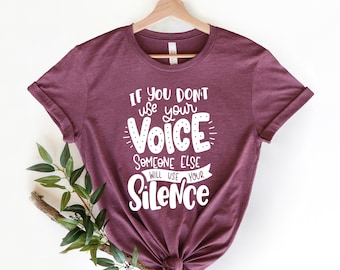 May include: A maroon t-shirt with the text "If you don't use your voice someone else will use your silence" in white.