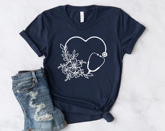 May include: A navy blue t-shirt with a white graphic of a stethoscope in the shape of a heart with floral accents.