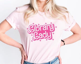 May include: A pink t-shirt with the text "Library Lady" in a pink retro font with sparkling stars around the text.