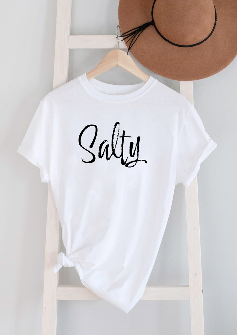 May include: White t-shirt with the word "Salty" written in black cursive script.