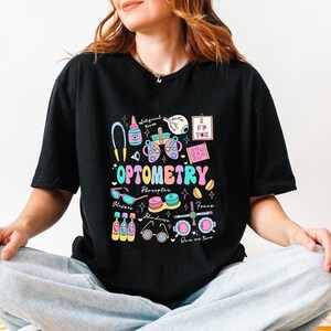 May include: Black t-shirt with a colorful illustration of optometry tools and the text "OPTOMETRY".