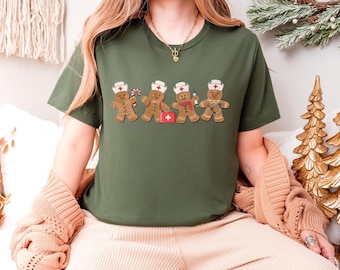 Puede incluir: Camiseta verde oliva con un diseño de hombrecitos de jengibre vestidos de enfermeros. Cada hombrecito de jengibre lleva un gorro de enfermera blanco y sostiene accesorios médicos. Un diseño divertido y festivo con temática sanitaria.