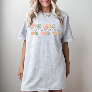May include: Gray oversized t-shirt with the text "THE BEACH is calling AND I MUST GO" in colorful letters.