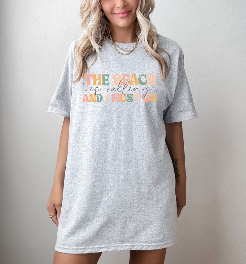 May include: Gray oversized t-shirt with the text "THE BEACH is calling AND I MUST GO" in colorful letters.