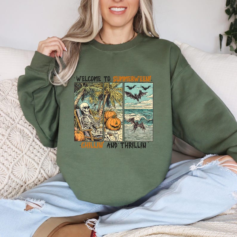 May include: Green crewneck sweatshirt with a graphic that says "WELCOME TO SUMMERWEEN!" and "CHILLIN AND THRILLIN". The graphic features a skeleton on a beach chair, pumpkins, palm trees, bats, and ocean waves.