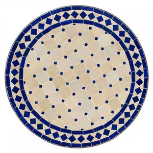 May include: Round table top with a white and blue mosaic tile design. The centre of the table top features a repeating pattern of small blue squares within larger white squares. The border of the table top features a repeating pattern of blue diamonds.