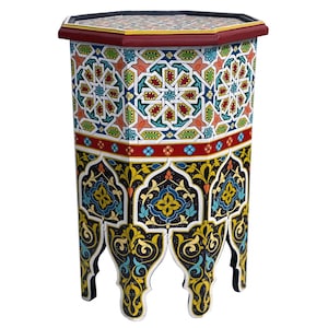 Peut inclure: Table octogonale avec des motifs géométriques complexes dans des tons de bleu, vert, rouge et jaune. La table a une base noire avec des sculptures ornées et un dessus rouge.