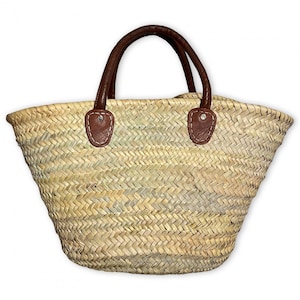 Könnte beinhalten: Gewebte Stroh-Tragetasche mit braunen Ledergriffen und Akzenten. Die Tasche hat ein breites, offenes Design und eignet sich zum Tragen verschiedener Gegenstände. Die Griffe sind mit genähten Lederaufnähern befestigt.