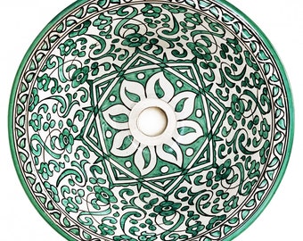 May include: A round ceramic sink with a green and white floral design. The sink has a drain hole in the center.