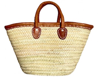 May include: A woven straw tote bag with brown leather trim and handles. The bag features a rounded shape with a sturdy base and two arched handles. The leather trim is stitched to the straw body, adding a decorative element.