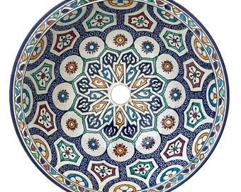 May include: A round, ceramic sink basin with a vibrant, intricate geometric pattern. The design features a central hole, surrounded by a complex arrangement of shapes in blue, white, yellow, red, and green. The rim is a deep blue.