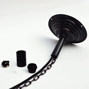 Op de afbeelding: Zwarte metalen plafondlamp met een ketting en een zwart elektriciteitskoord. De lamp heeft een ronde, platte basis met een decoratief, gelaagd ontwerp. De lamp wordt geleverd met een zwarte elektrische fitting en een zwart elektriciteitskoord.