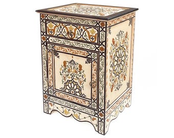 May include: A cream-colored, hand-painted wooden nightstand with intricate floral and geometric designs in brown, gold, and black. The nightstand features a drawer and a cabinet door, with a dark brown top and scalloped base.