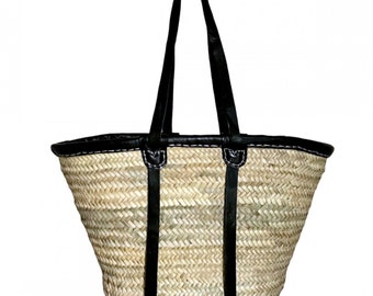 May include: A natural woven straw tote bag with black leather handles and trim. The bag has a white stitched border.