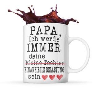 Peut inclure: Mug en céramique blanche avec le texte "PAPA, Ich werde' IMMER deine kleine Tochter FINANZIELLE BELASTUNG sein" en noir, avec des cœurs rouges. Une éclaboussure de liquide brun foncé au-dessus de la tasse.