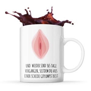 Könnte beinhalten: Weiße Keramiktasse mit einer pinkfarbenen anatomischen Illustration und dem Text "UND WIEDER SIND 365 TAGE VERGANGEN, SEITDEM DU AUS EINER SCHEIDE GEPLUMPT BIST".