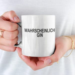 Op de afbeelding: Witte keramische mok met zwarte tekst die "Wahrscheinlich Gin" zegt.