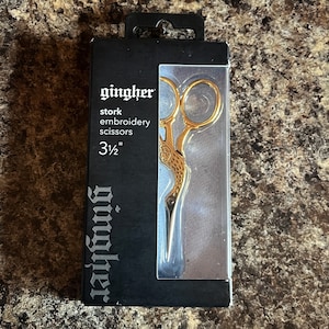 May include: Gold stork embroidery scissors in a black and silver package. The package says "gingher stork embroidery scissors 3 1/2""
