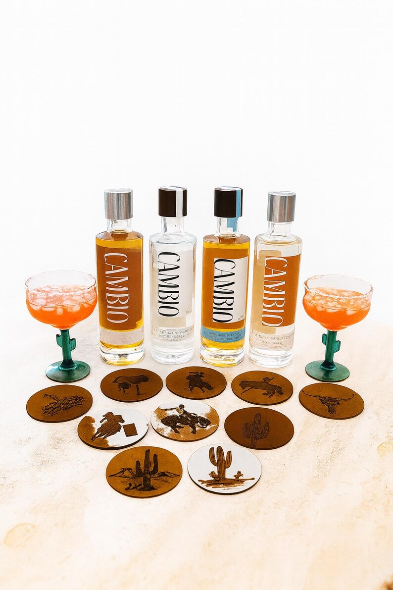 Peut inclure: Quatre bouteilles de tequila Cambio avec des bouchons argent&eacute;s et noirs, accompagn&eacute;es de deux cocktails dans des verres en forme de cactus verts. Des dessous de verre bruns avec des motifs western sont dispos&eacute;s.