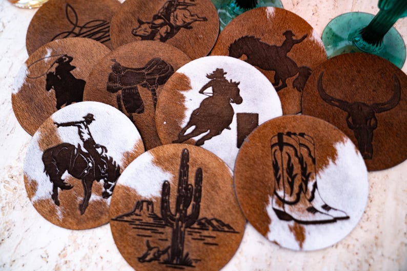 Peut inclure: Ensemble de dessous de verre ronds avec un motif de peau de vache marron et blanc. Chaque dessous de verre pr&eacute;sente une silhouette diff&eacute;rente de cowboy, de cheval ou de th&egrave;me western, comme un cactus ou des bottes de cowboy.