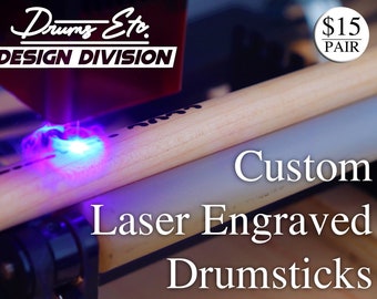 May include: A laser engraver is engraving a wooden drumstick with a blue laser beam. The text "Drums Etc. DESIGN DIVISION" is visible on the engraver. The text "Custom Laser Engraved Drumsticks" is visible below the drumstick. The text "$15 PAIR" is visible in the upper right corner of the image.
