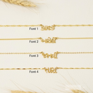 May include: Four gold-toned necklaces, each featuring a unique nameplate pendant with different script lettering styles. The necklaces are labeled Font 1, Font 2, Font 3, and Font 4, showcasing distinct chain designs and custom nameplate typography.