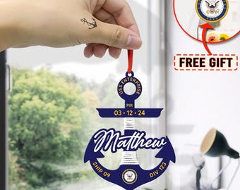 May include: A blue and gold anchor-shaped Christmas ornament with the text "USS ENTERPRISE PIR 03.12.24 Matthew SHIP 09 DIV 123". The ornament features a white rope design and a small US Navy seal.