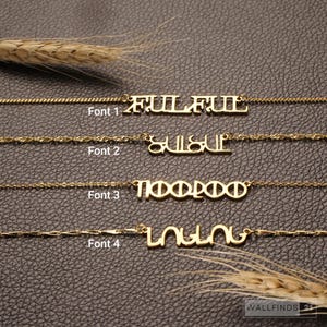 May include: Four gold-toned necklaces with custom nameplates, each featuring a distinct font style labeled Font 1, Font 2, Font 3, and Font 4. The necklaces are displayed horizontally, showcasing varied chain links and unique lettering designs for each piece.
