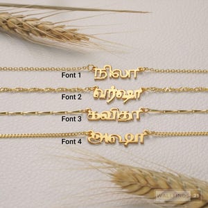 Pode incluir: Quatro colares dourados com pingentes de nome personalizados em escrita tâmil, cada um exibido com um estilo de corrente único e rotulado como Font 1, Font 2, Font 3 e Font 4. Os colares estão dispostos horizontalmente, mostrando designs de letras distintos.