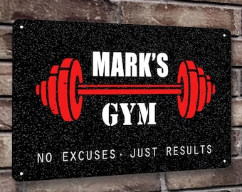 May include: Black metal sign with white text that reads "Mark's Gym No Excuses Just Results". The sign features a red barbell with weights on each end.