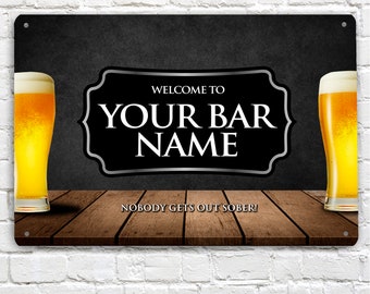 May include: Black and white sign with a silver border that says "Welcome to Your Bar Name" with a beer glass on each side. The sign is on a wooden surface and says "Nobody gets out sober!"