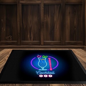 May include: Black rectangular mat with a neon sign design. The sign features a cocktail glass with a cherry and lime, surrounded by a purple oval and the words "Manhattan Cocktail Bar."
