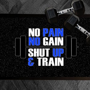 May include: A rectangular black floor mat featuring a white and blue graphic of a barbell and the text NO PAIN NO GAIN SHUT UP & TRAIN. Two black dumbbells are positioned on the top right corner of the mat, which has a textured surface.
